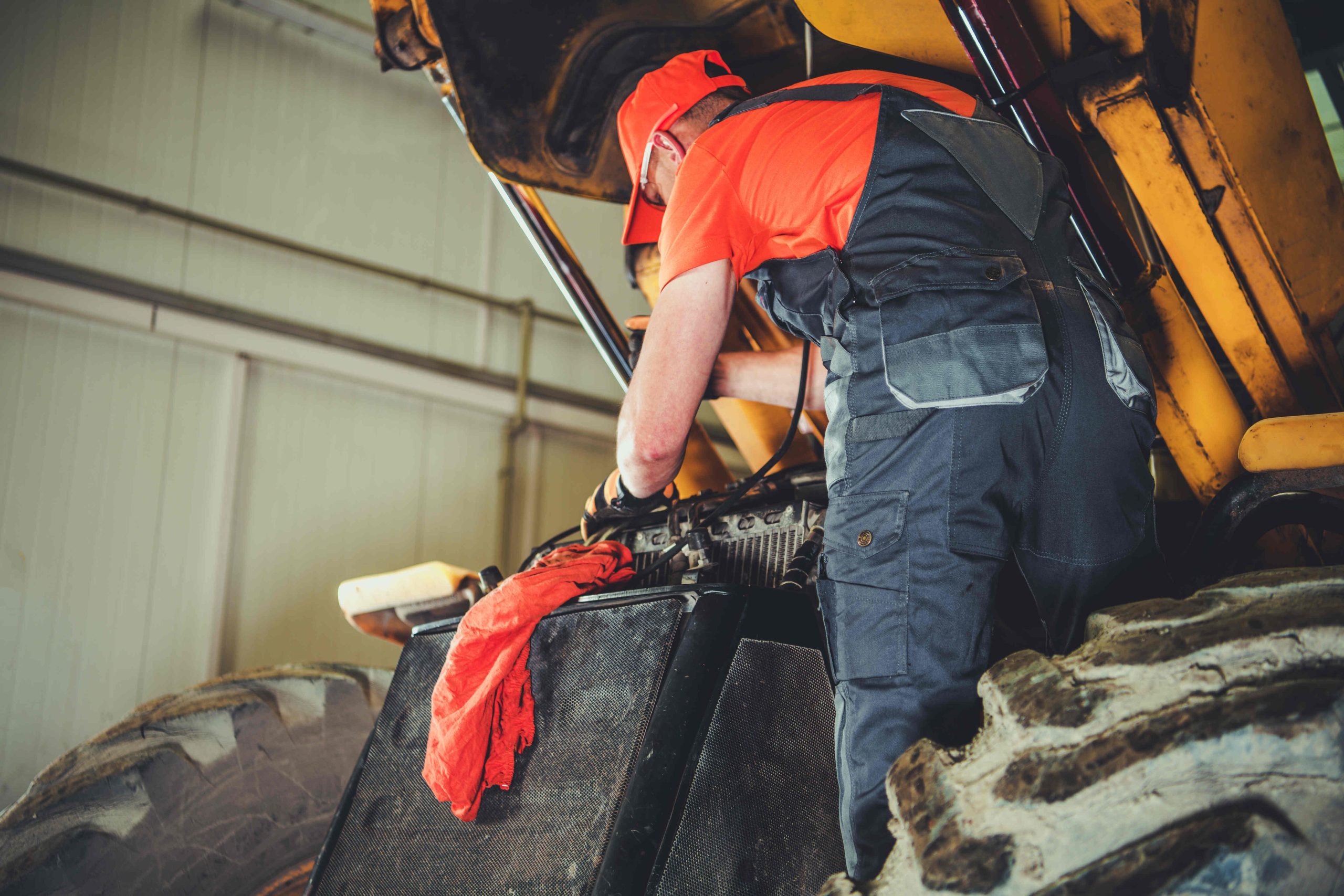 caucasian heavy machinery mechanic performing tractor maintenance